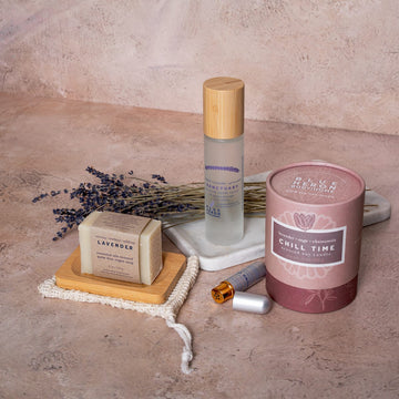 Sanctuary Room Spray, Chill Time Candle, Ground Control Aromaboost Inhaler, and Lavender Earth soap on flat surface with lavender